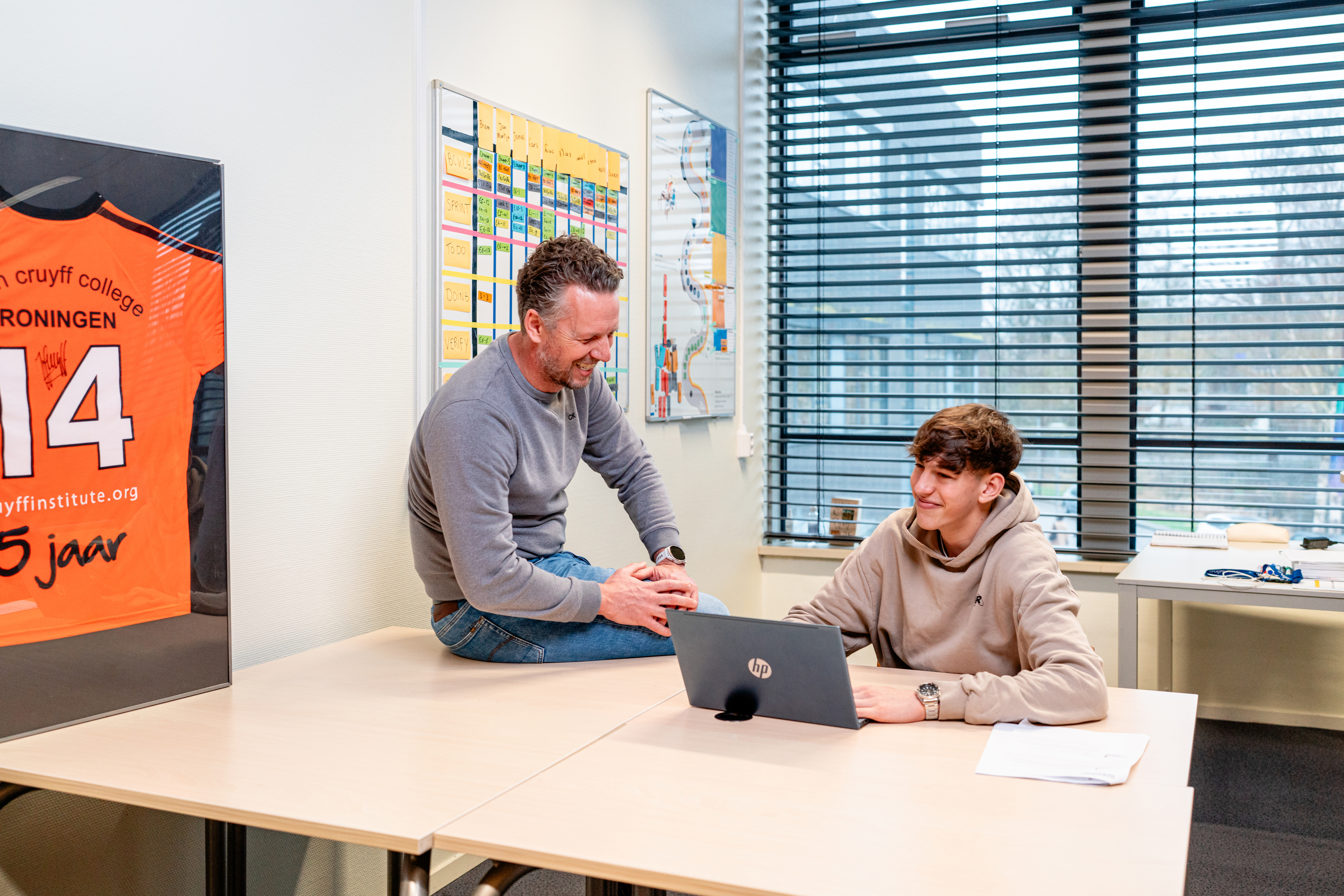 Docent en student in gesprek over marketing en communicatie binnen het Johan Cruyff College van Noorderpoort.