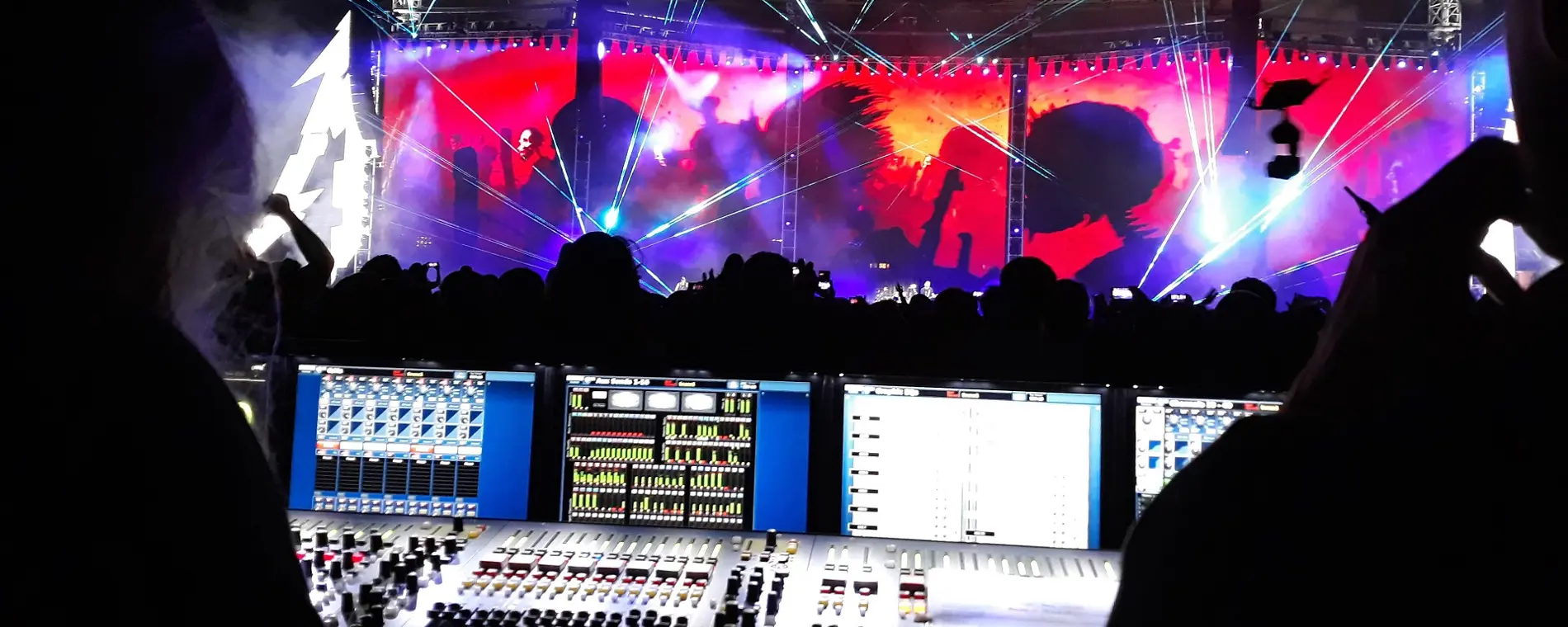 Technicus bedient geluidstechniek tijdens een live muziekoptreden in een groot muziekcentrum