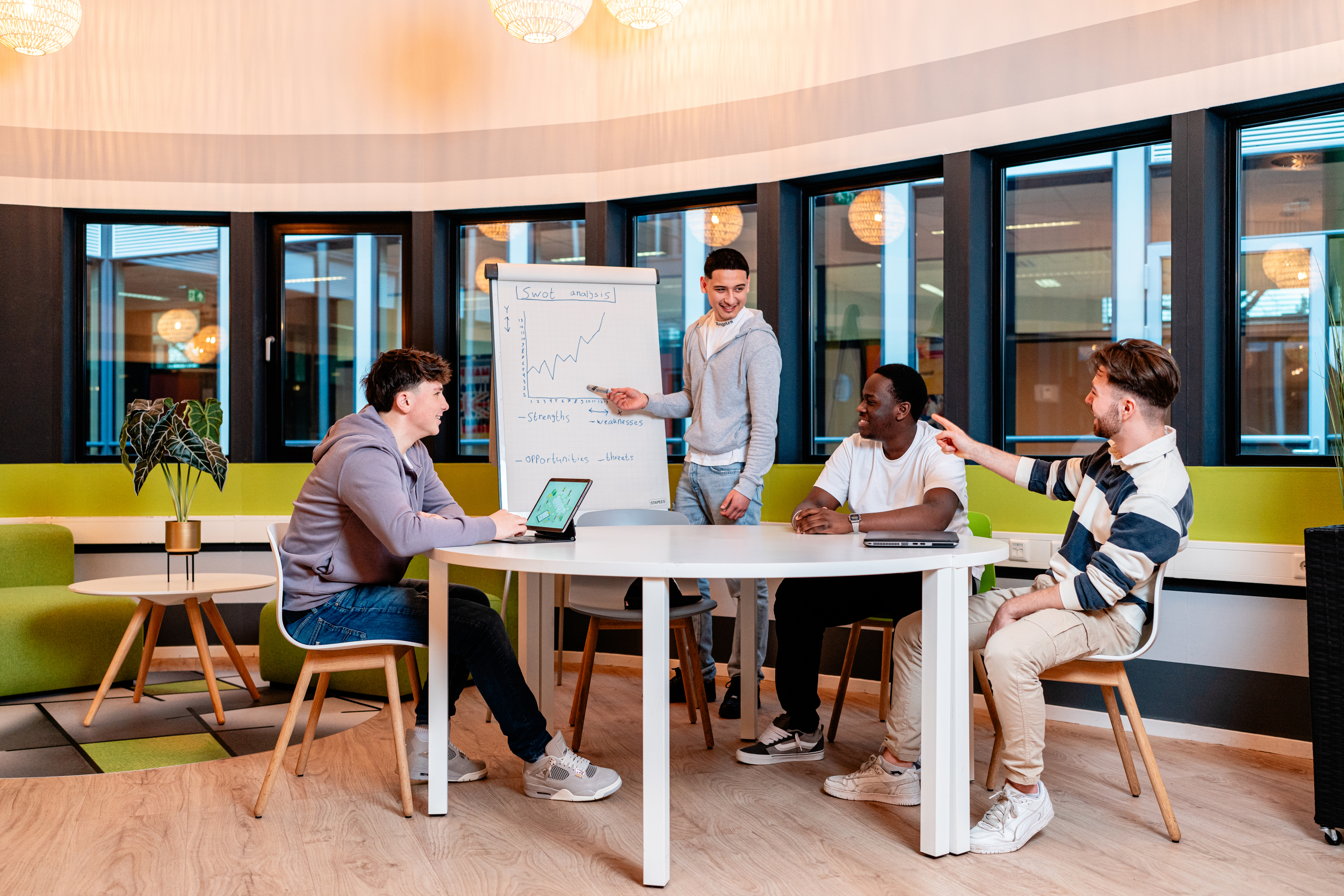 Studenten bespreken zakelijke grafiek tijdens presentatie in moderne leeromgeving van Noorderpoort