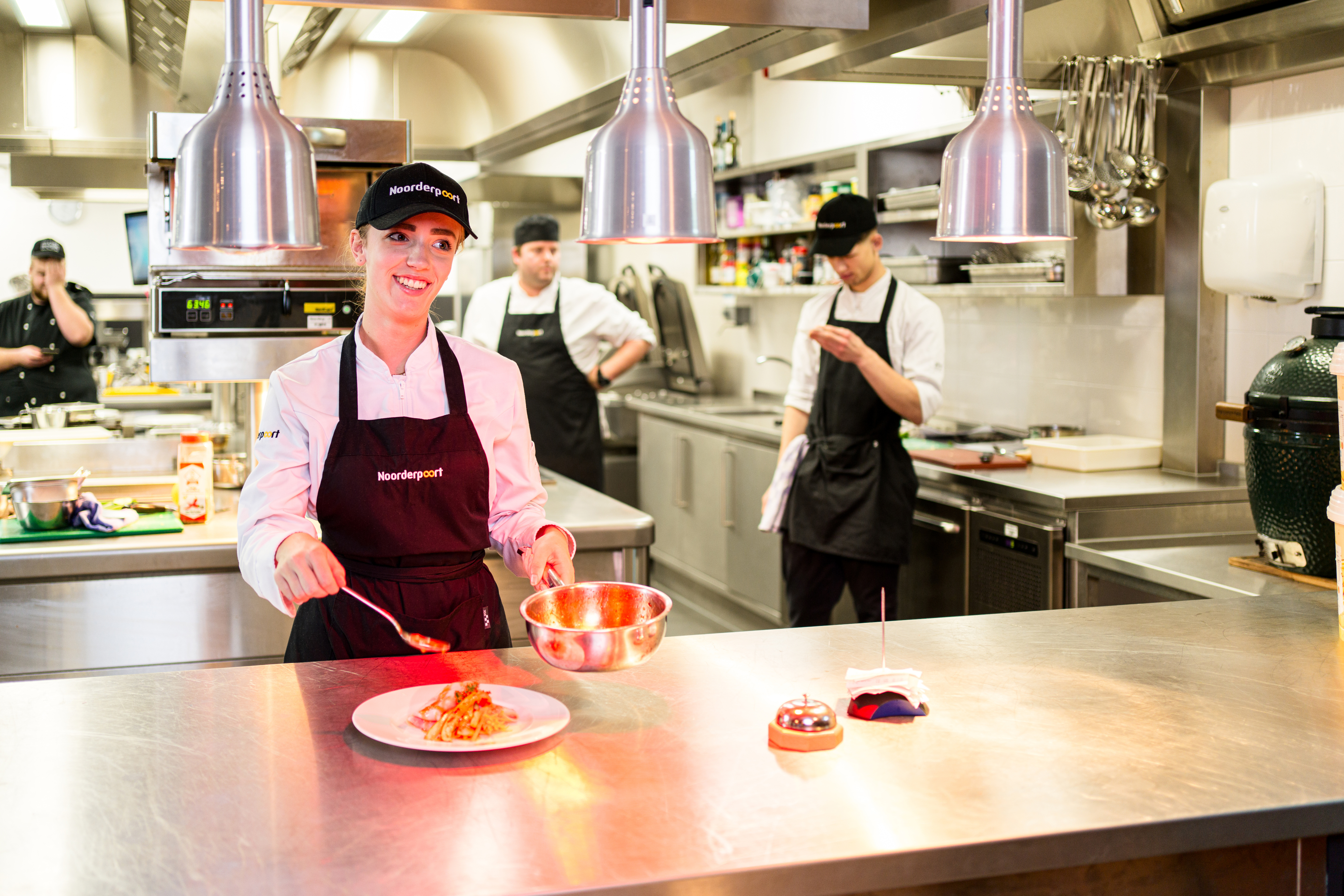 Een kok bereidt zelfstandig een gerecht in een professionele keuken tijdens praktijkles horeca.