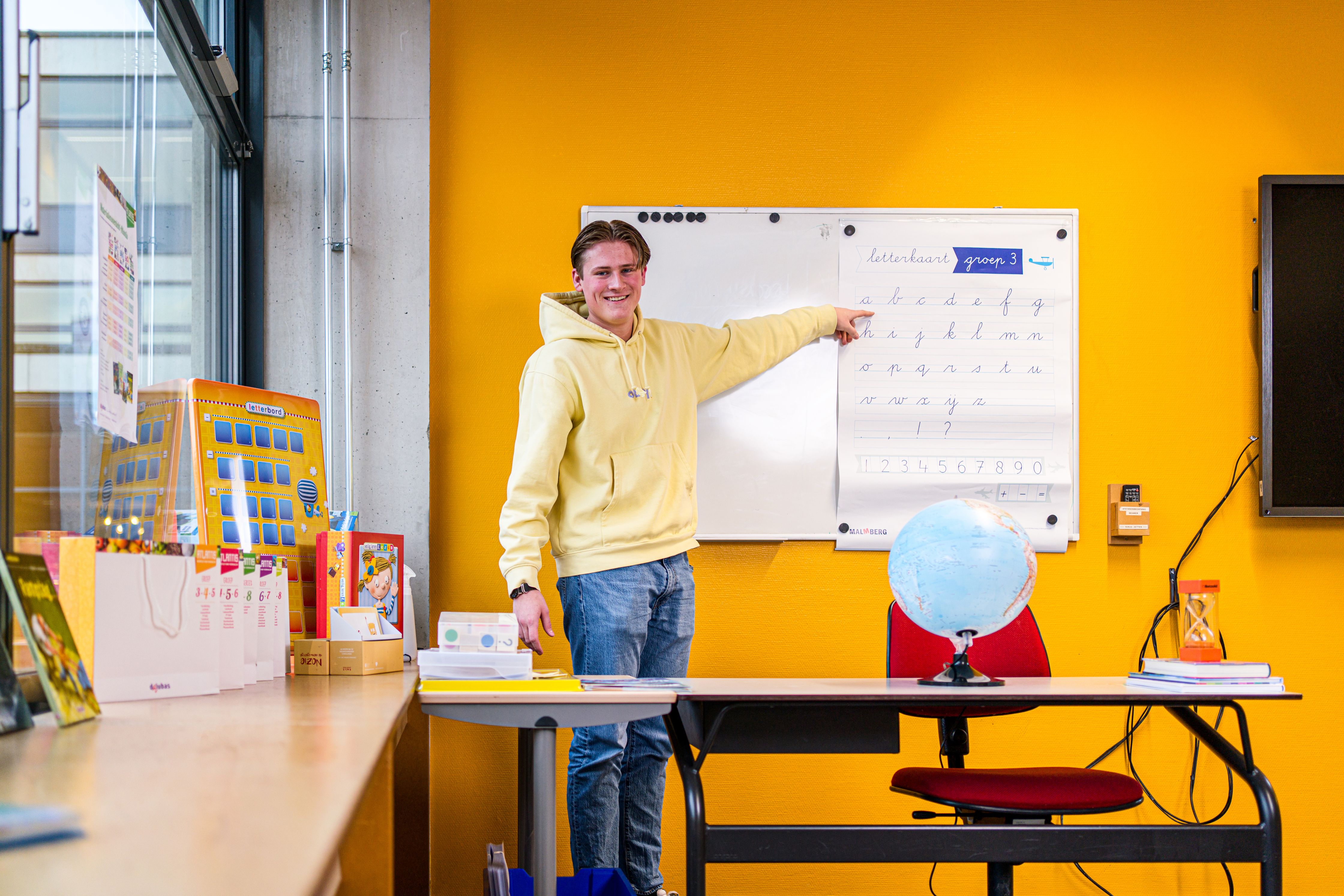 Student wijzend naar een whiteboard met schrijfoefeningen in een klaslokaal van Noorderpoort
