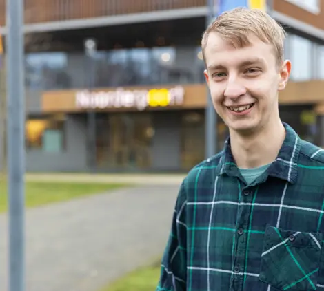 Dennis, lid van het inspiratieteam NEXT, staat voor de hoofdingang van Noorderpoort in Stadskanaal.