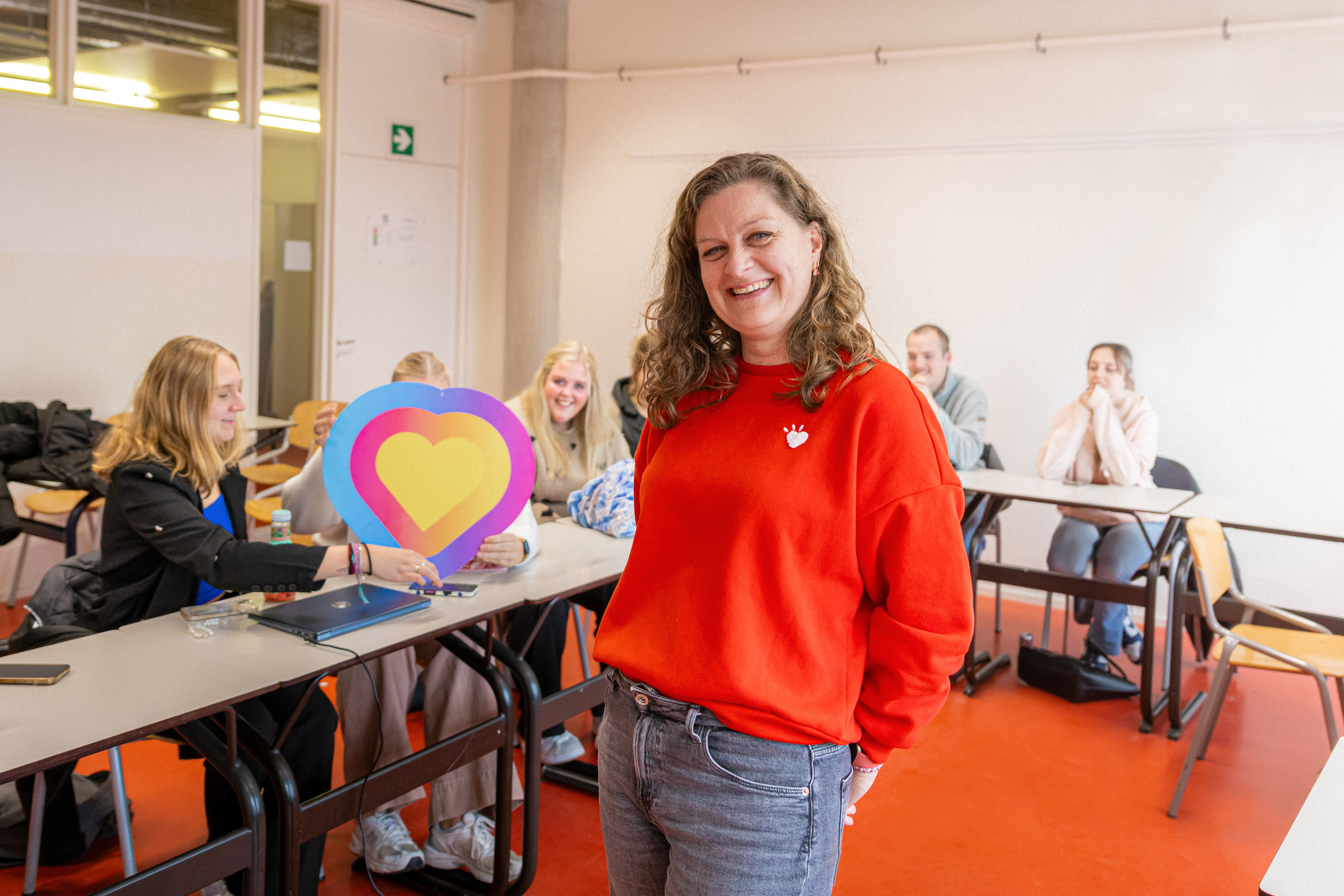 Betrokken docent in een klaslokaal met studenten die samenwerken aan een kleurrijk hartproject