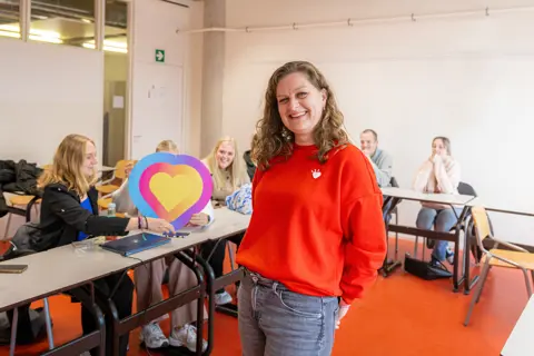 Betrokken docent in een klaslokaal met studenten die samenwerken aan een kleurrijk hartproject